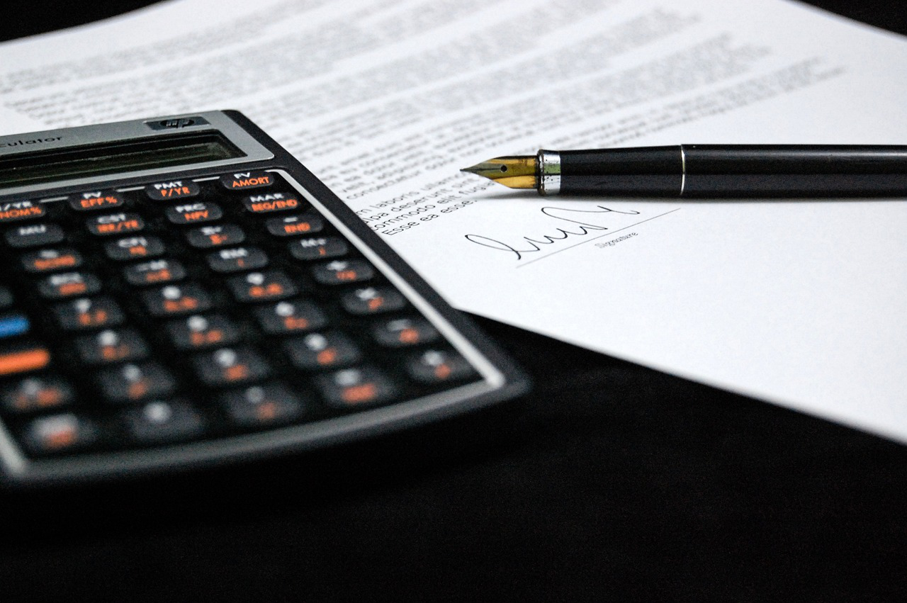 a calculator and pen on top of a signed document