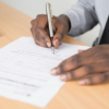Close-up of a person signing a document with a pen