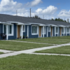 Row of modern, single-story affordable housing units with well-maintained lawns
