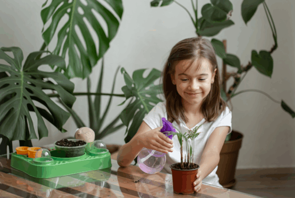 Young girl practicing green living for kids by watering indoor plants at home, encouraging eco-friendly habits from an early age.
